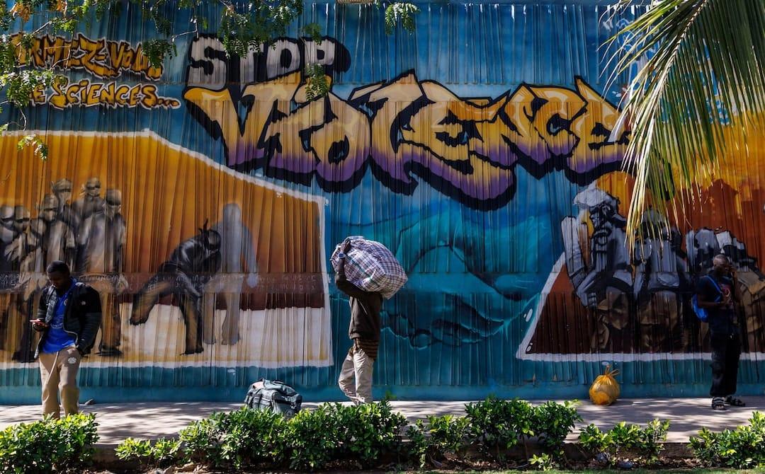 Senegal Campus Protests Leave Student Dead Amid Rising Unrest A student carries a bag with his belongings as he walks past a graffiti mural reading “Stop Violence” outside the Cheikh Anta Diop University campus that was closed today until further notice after clashes with security forces left one student dead during protests in which demonstrators have been demanding stipends and other financial support amid the government’s ongoing fiscal challenges in Dakar, Senegal, February 10, 2026. | REUTERS/Zohra Bensemra